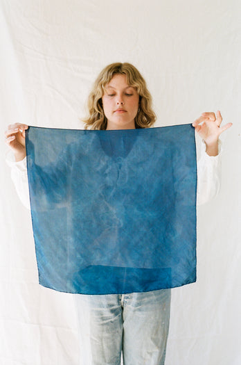 a woman holding the naturally dyed indigo fabric