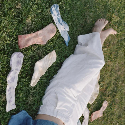 a person laying down on the ground with naturally dyed socks